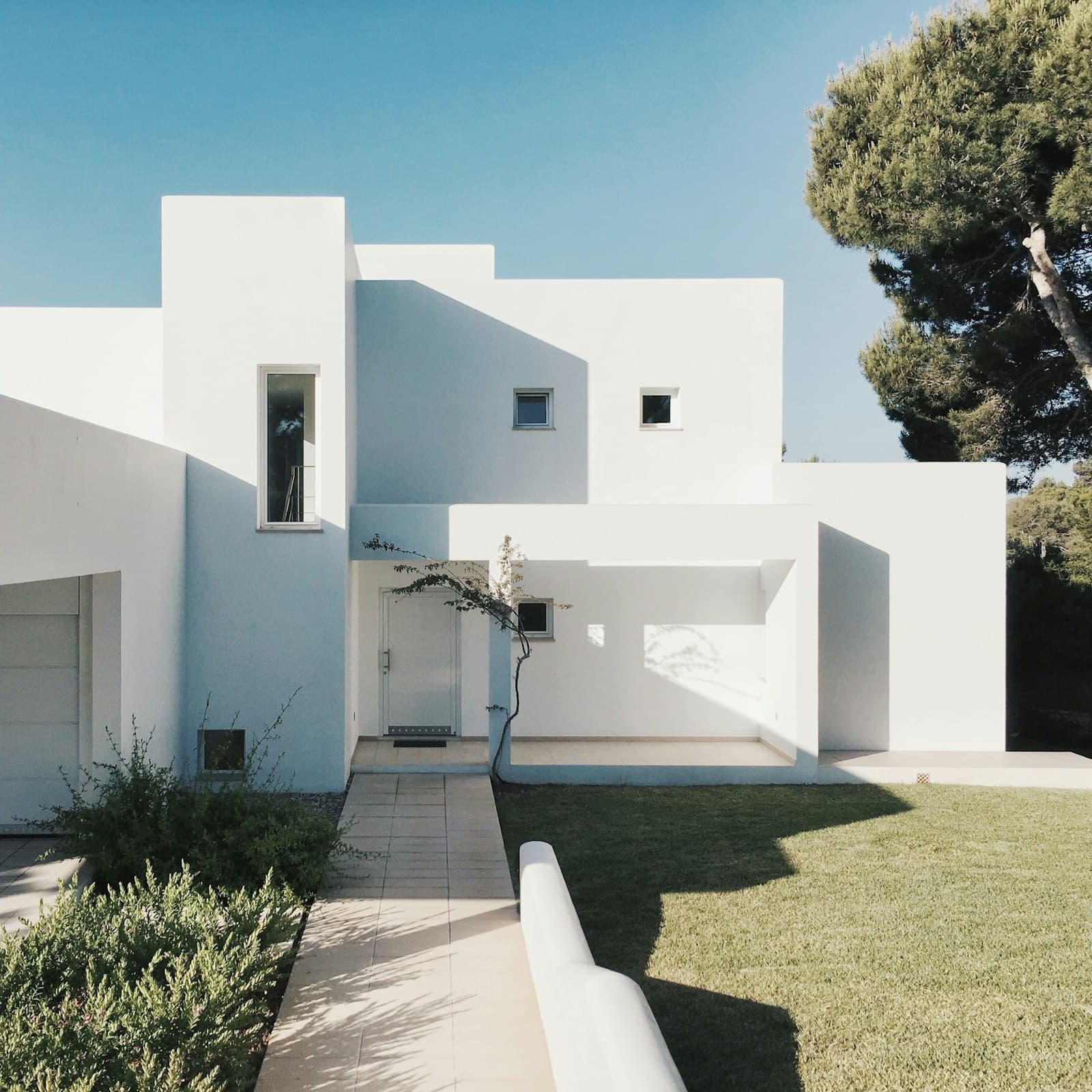 A bright white home in full sunshine with a green lawn